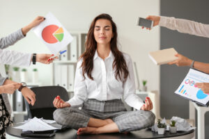 stress im Business ist nicht nur ein Thema bei M&auml;nnern. Die Frau versucht trotz viel Arbeit in ihrer Mitte zu bleiben.