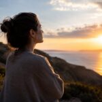 Woman letting go of control while finding inner peace beside the ocean at sunset.
