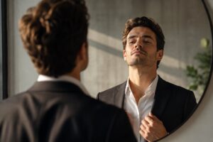 Narzissmus symbolisch dargestellt durch einen selbstbewussten Mann, der sein Spiegelbild betrachtet.